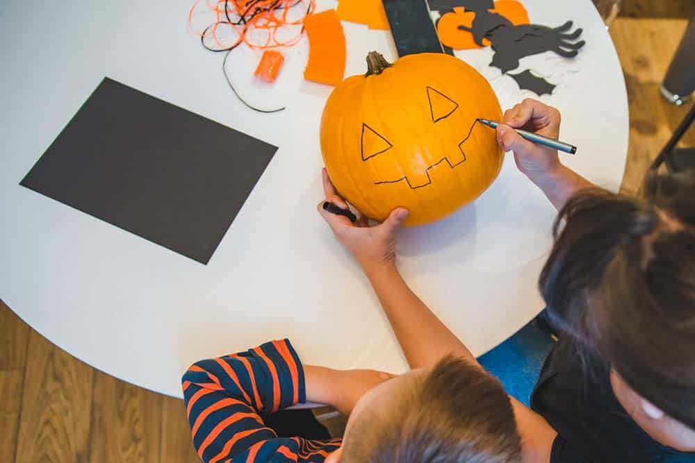 Enfant qui peint une citrouille pendant un atelier Halloween en entreprise