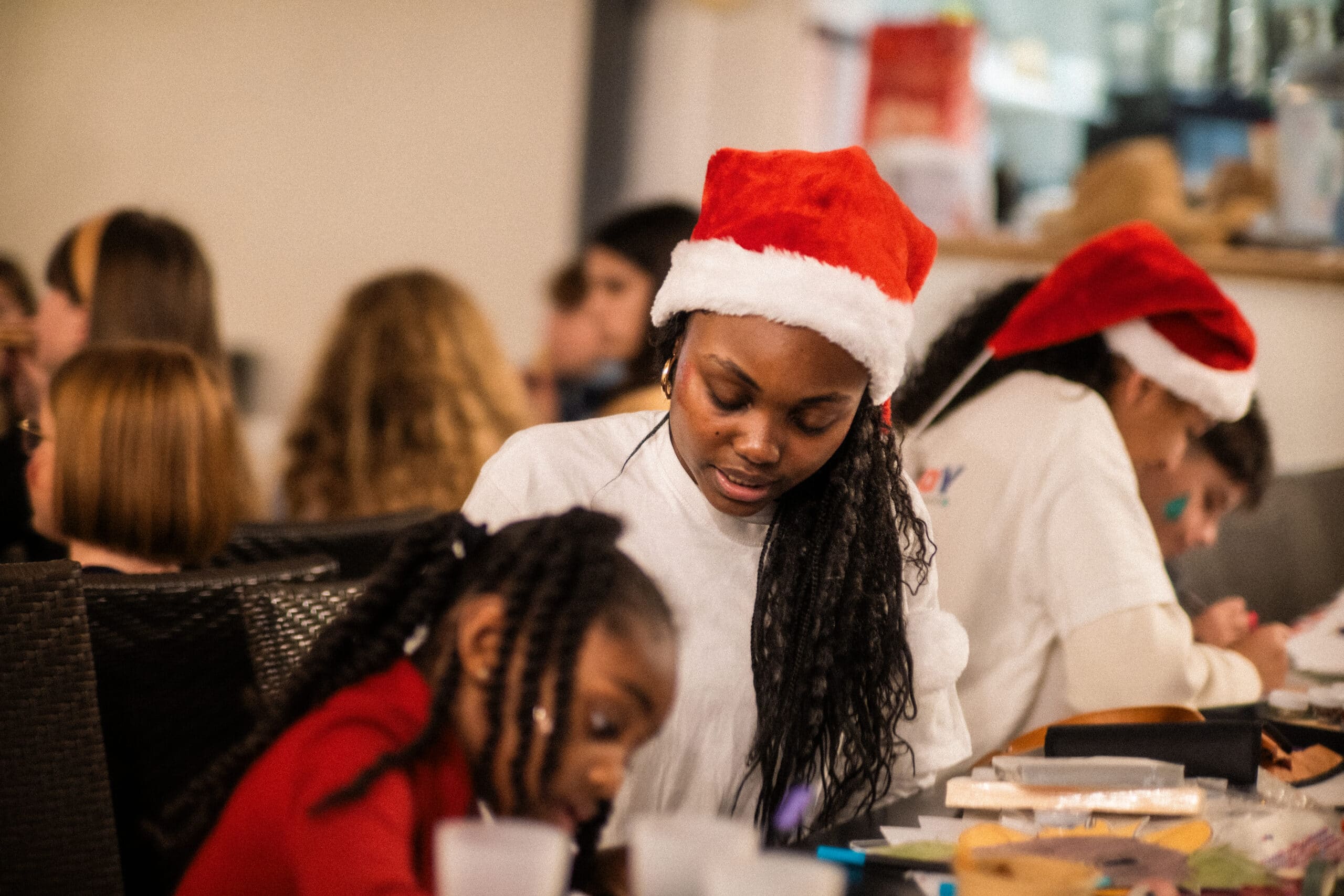 Noël 2 Enfant coiffée d'un bonnet de Noël participant à un atelier créatif lors d'un arbre de Noël d'entreprise