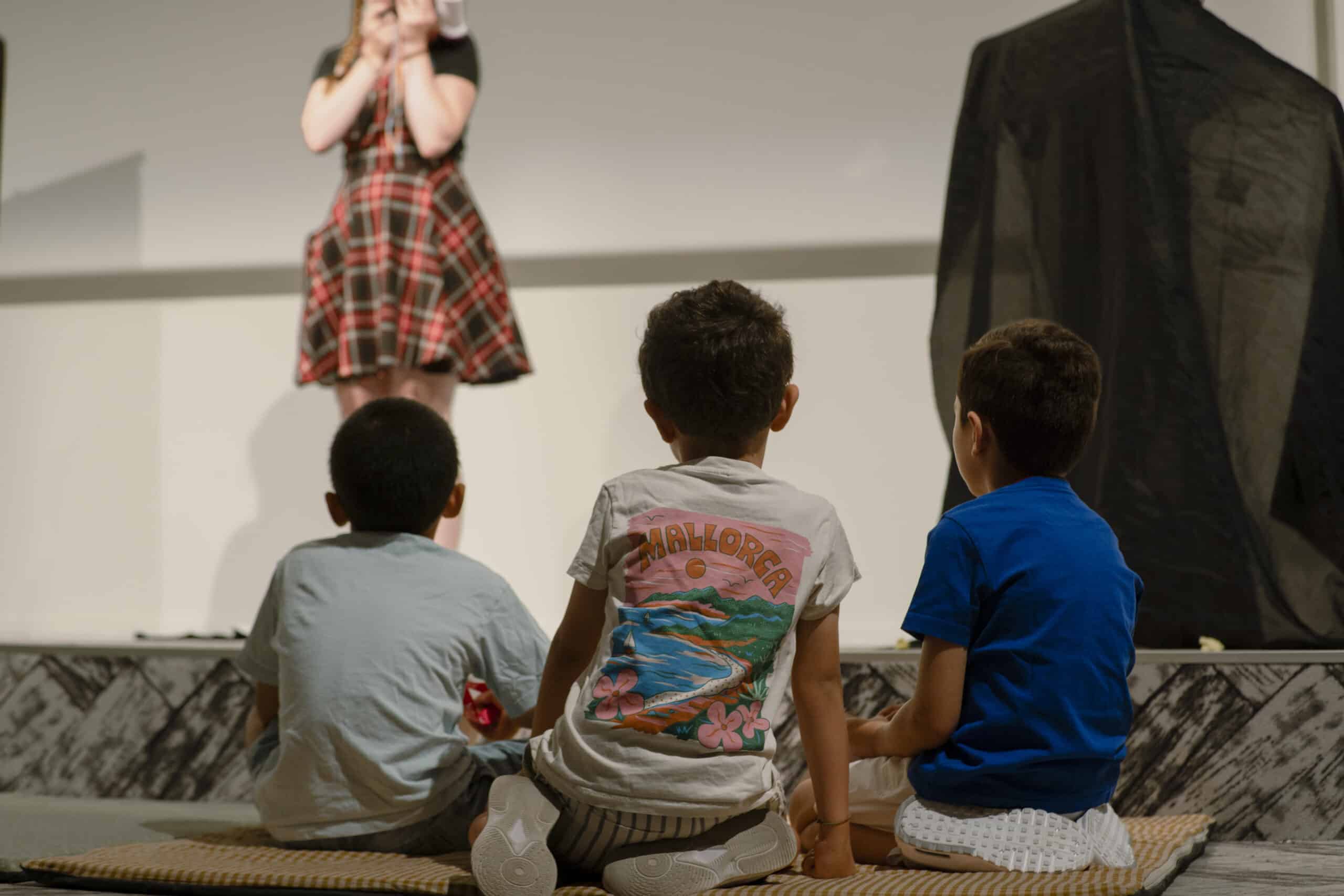 Enfants des salariés assis dans un espace collectif d'entreprise pendant un spectacle, lors d'une journée d'accueil KidosDay