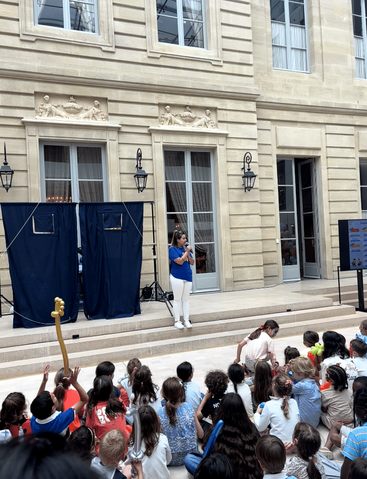 Une animatrice KidosDay présente le spectacle aux enfants depuis la scène, lors de la journée des familles AXA