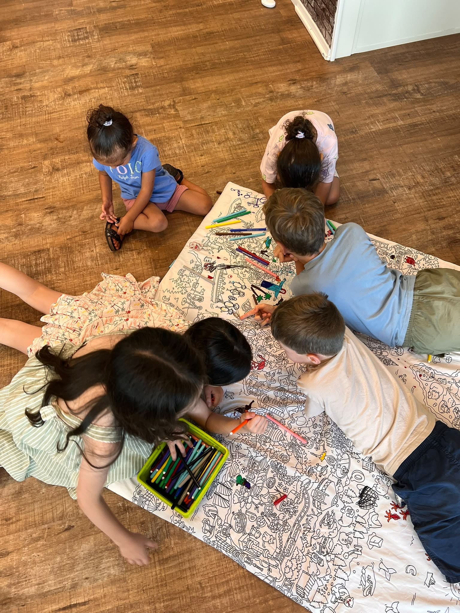 Enfants allongés sur une grande nappe à colorier pendant l'accueil canicule chez LiveRamp